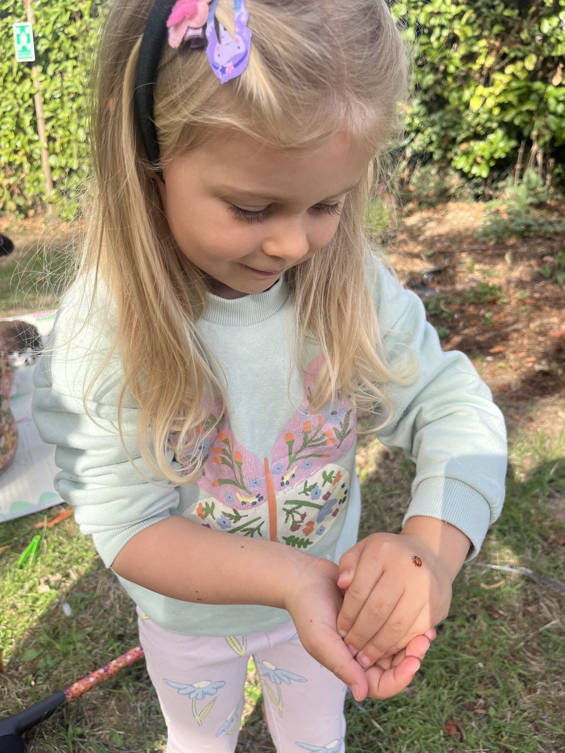 A child holding and exploring a tiny treasure outdoors