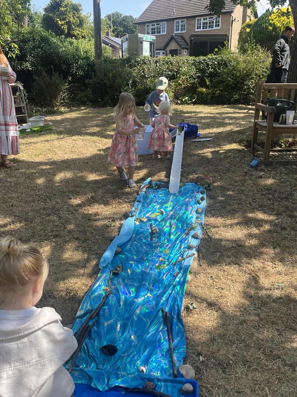 Children exploring a long blue pretend stream outdoors
